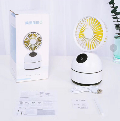 Dark grey fan humidifier with a round fan head and spherical base, emitting mist, on a white desk. - Image 6