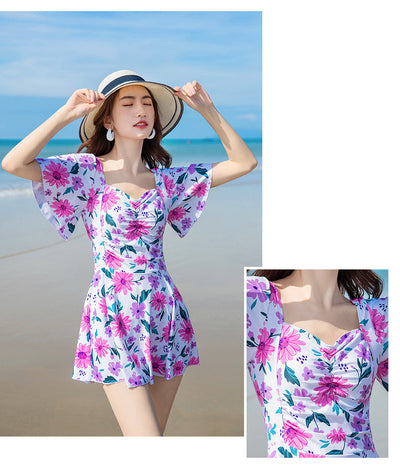 Woman in a light blue floral dress-style swimsuit with short sleeves and a sweetheart neckline on a beach. - Image 12
