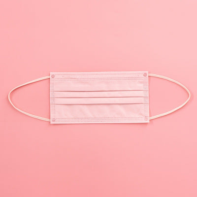 Light pink disposable face mask with white ear loops, featuring pleats for a comfortable fit. - Image 2