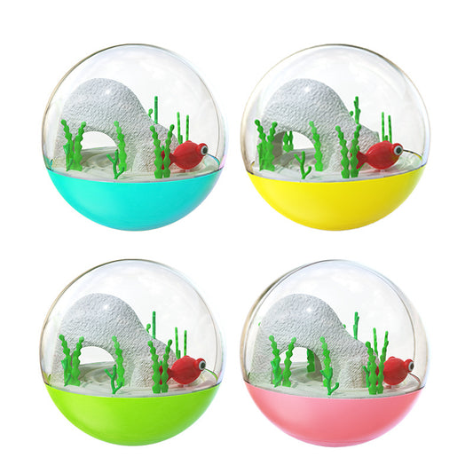 Clear and teal cat toy tumbler with a red fish and green seaweed inside, observed by a curious grey cat.