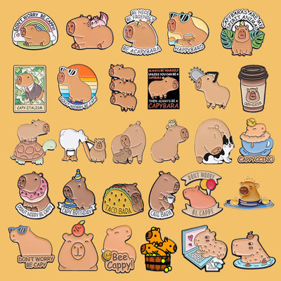 Cute capybara enamel brooch wearing a pink donut with sprinkles and "DONUT WORRY BE CAPPY" text. - Image 36