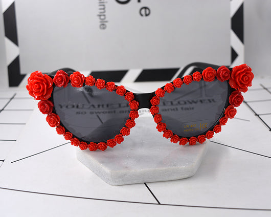 Black cat-eye sunglasses with dark lenses, adorned with small red rose embellishments along the frames. - Image 4