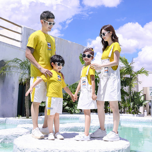 Family of three in matching yellow t-shirts and white outfits by a pool. Father and son wear shorts, mother and daughter wear overall dresses. - Image 5