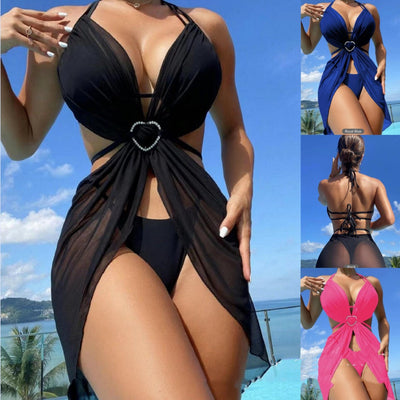 White three-piece halter neck bikini and sheer cover-up set with a heart-shaped embellishment, laid flat on wood.