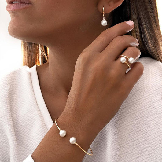 Gold-tone open cuff bracelet, matching open ring, and dangle earrings, all featuring white faux pearls.
