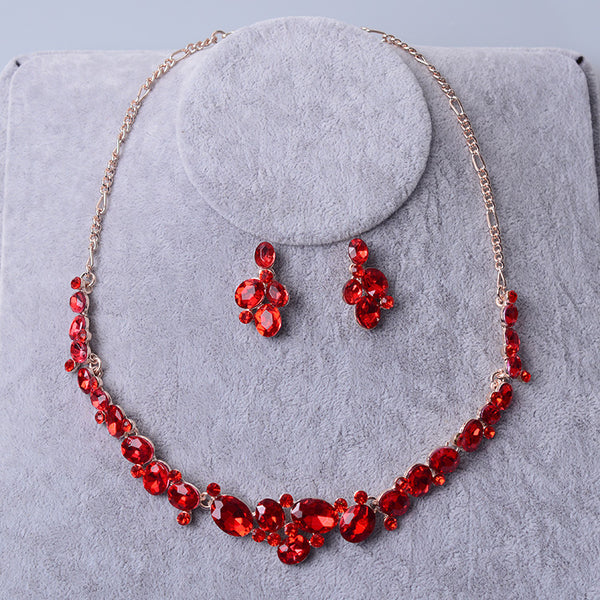 Silver-tone bridal necklace and matching drop earrings set with clear oval and round rhinestones, displayed on a gray velvet stand.