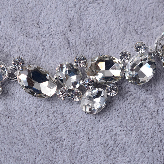Silver-tone bridal necklace and matching drop earrings set with clear oval and round rhinestones, displayed on a gray velvet stand. - Image 3