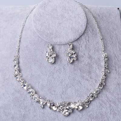Silver-tone bridal necklace and matching drop earrings set with clear oval and round rhinestones, displayed on a gray velvet stand. - Image 5