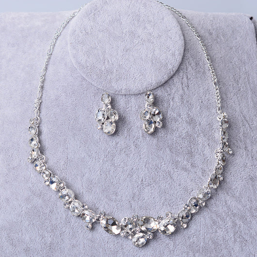 Silver-tone bridal necklace and matching drop earrings set with clear oval and round rhinestones, displayed on a gray velvet stand. - Image 5