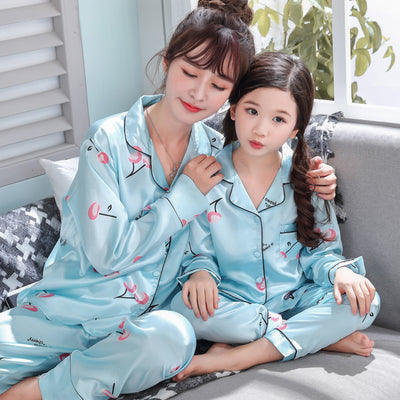 Mother and daughter in matching light blue satin pajamas with pink cherry print, sitting on a gray sofa. - Image 9