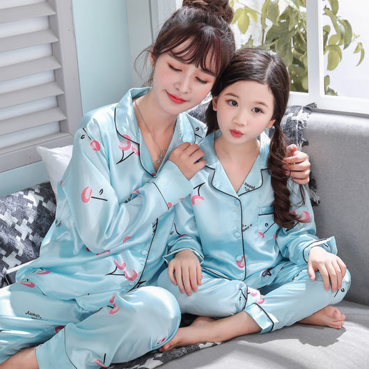 Mother and daughter in matching light blue satin pajamas with pink cherry print, sitting on a gray sofa. - Image 9
