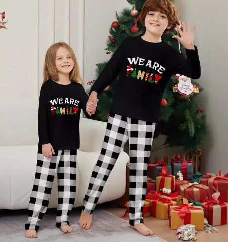 Family of four wearing matching black long-sleeve pajamas with "WE ARE FAMILY" text and black and white plaid bottoms. - Image 6