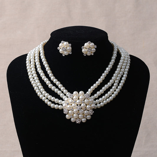 Luxury bridal pearl necklace and earring set with a multi-strand design and rhinestone flower accent.