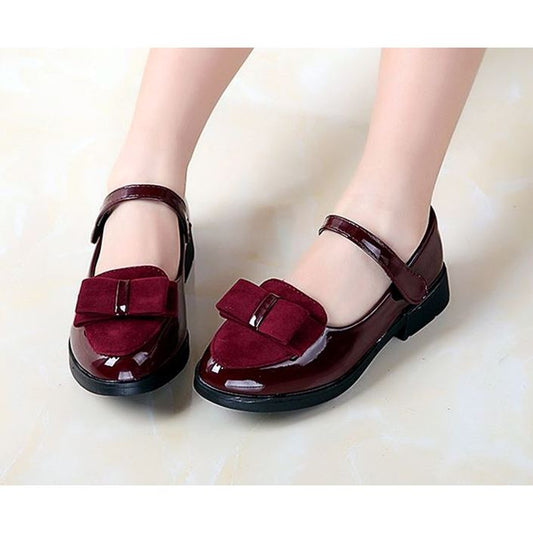 Black patent Mary Jane shoes for girls with a strap, round toe, and a black suede bow with a silver accent. - Image 2