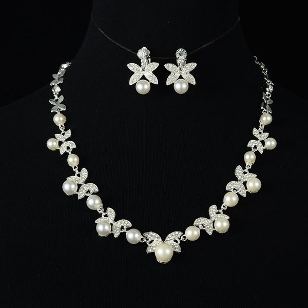 Red pearl and rhinestone necklace and earrings set with gold-toned clover designs, perfect for a wedding or special occasion.
