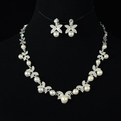 Red pearl and rhinestone necklace and earrings set with gold-toned clover designs, perfect for a wedding or special occasion.