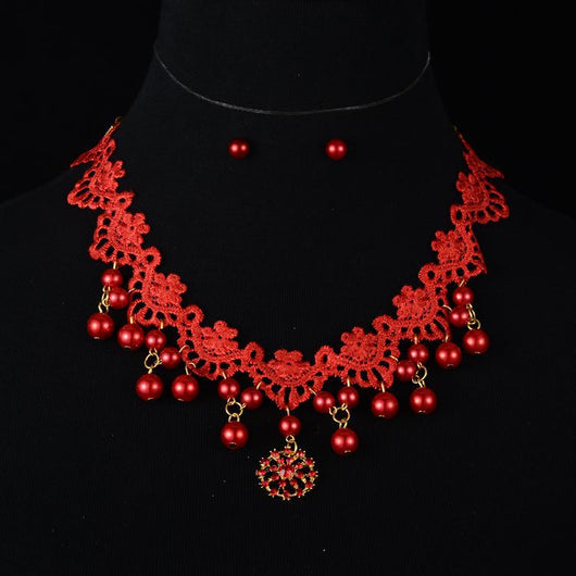 White lace and pearl necklace set with matching stud earrings, featuring a snowflake pendant, on a black display.
