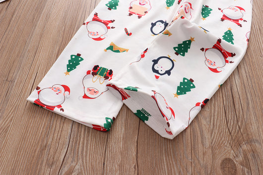 Family of four wearing matching white Christmas pajamas with Santa, penguin, reindeer, and tree print. - Image 12