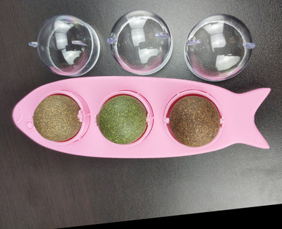 Pink fish-shaped cat molar stick toy with three compartments holding green and brown catnip or silvervine balls. Three clear plastic dome covers are shown. - Image 9