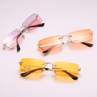 Frameless rectangular sunglasses with pink gradient lenses, gold-tone metal arms, and rhinestone embellishments.