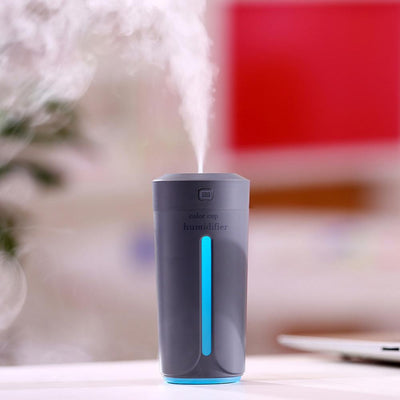 White mini USB ultrasonic humidifier with a green LED light strip, emitting mist, on a white surface. - Image 5