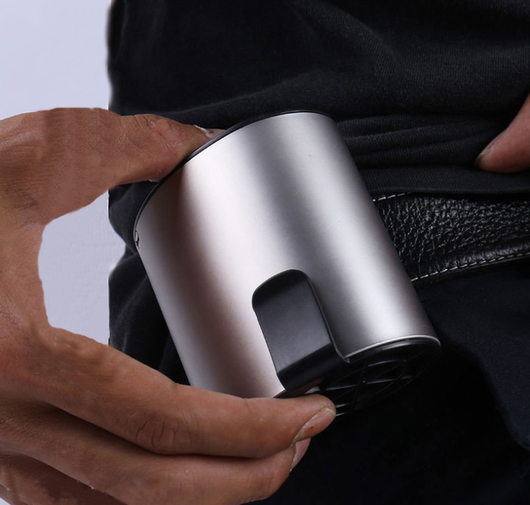 Close-up of a finger pressing the power button on a silver-grey portable waist fan with a black fan grill. - Image 5