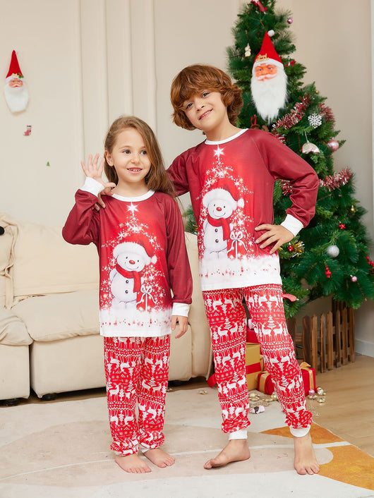 Family of four wearing matching red Christmas pajamas with snowman tops and reindeer fair isle pants, sitting by a Christmas tree. - Image 6