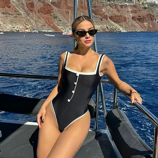 Woman in a white one-piece swimsuit with black trim and decorative buttons, sitting on a boat. - Image 10