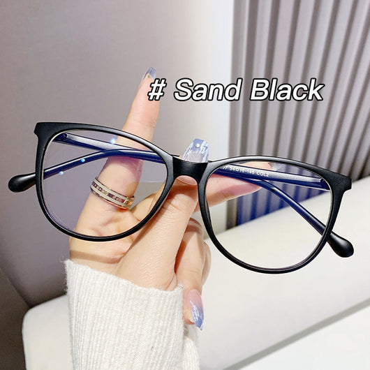 Black full-frame round anti-blue light glasses held by a hand with a gold ring and light blue gradient nails. - Image 7