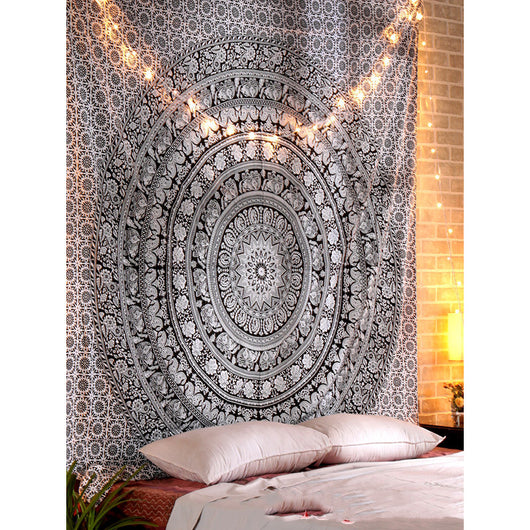 Black and white mandala tapestry with string lights hanging above a bed with blue and white patterned pillows. - Image 8