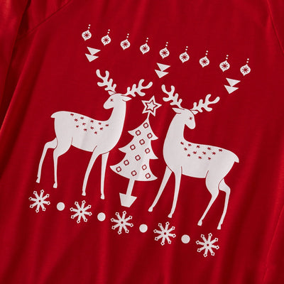 Family of four wearing matching red Christmas pajamas with white reindeer and tree patterns, standing by a decorated tree. - Image 9