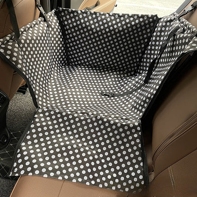 Brown pet car mat with colorful dog pattern installed in a car's rear seat, protecting upholstery.