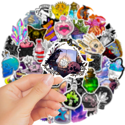 A hand holds a gothic-themed sticker featuring a raven, skull, and crystals, with a pile of 50 assorted waterproof stickers in the background. - Image 11