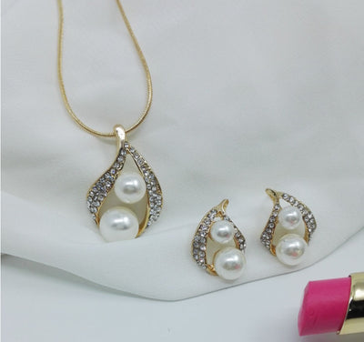 Gold-tone teardrop necklace and matching stud earrings set with white pearls and clear rhinestones, displayed on black. - Image 8