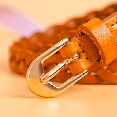 Women's braided brown leather belt with a D-shaped gold-tone pin buckle, coiled on a peach background. - Image 5
