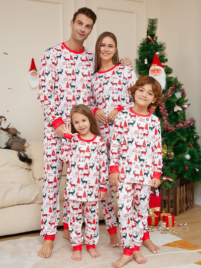 Young girl in white Christmas pajamas with red deer and tree print, red trim, standing by a decorated tree. - Image 2