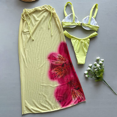 Woman in a light yellow three-piece bikini with an underwire top, matching bottoms, and a sheer floral sarong skirt. - Image 4
