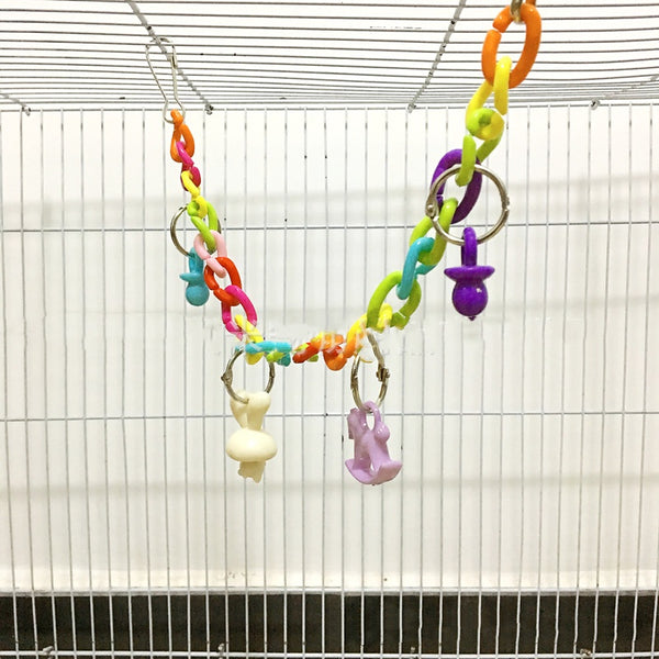 Colorful acrylic chain suspension bridge swing toy with hanging charms for parrots, installed in a white bird cage.