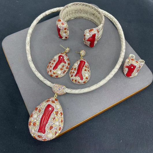 Four-piece jewelry set with white snakeskin leather, red coral-like inlays, pearls, and gemstones.