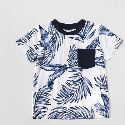 Young boy wearing a white short-sleeve t-shirt with blue tropical leaf print and a black chest pocket. - Image 23