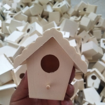 Unfinished wooden birdhouse with a circular entrance hole and a small perch, held by a hand.