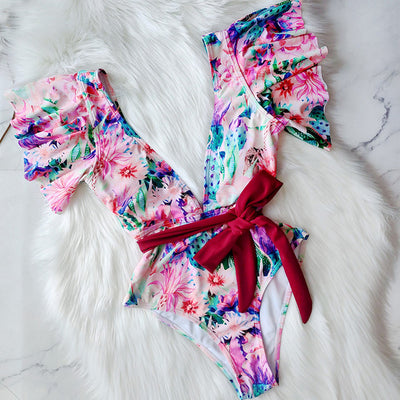 Coral one-piece swimsuit with deep V-neck, ruffled sleeves, and tie-front waist, featuring pink and teal floral print. - Image 3
