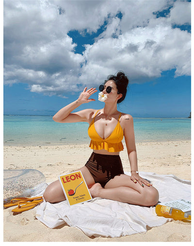 Woman in a yellow ruffled bikini top and dark brown high-waisted bottoms sitting on a beach. - Image 11