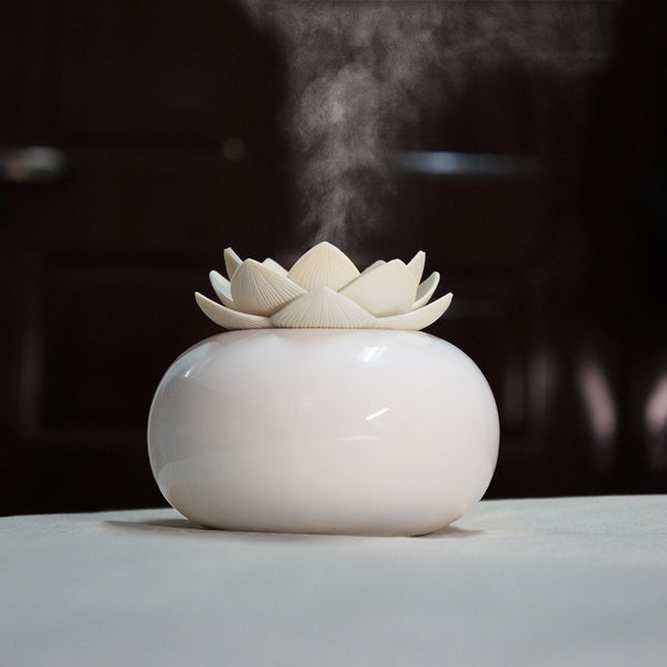 White ceramic lotus aromatherapy humidifier emitting a fine mist, perfect for home or office decor.