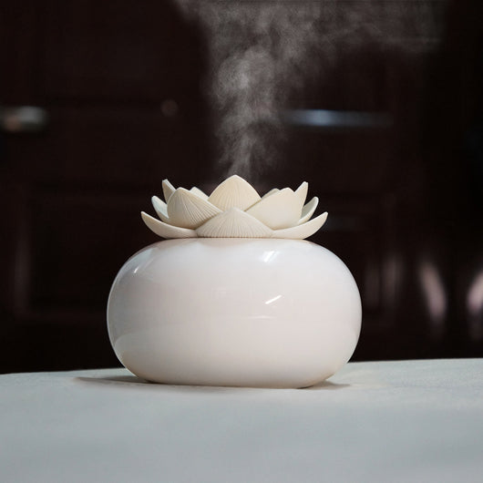 White ceramic lotus aromatherapy humidifier emitting a fine mist, perfect for home or office decor.