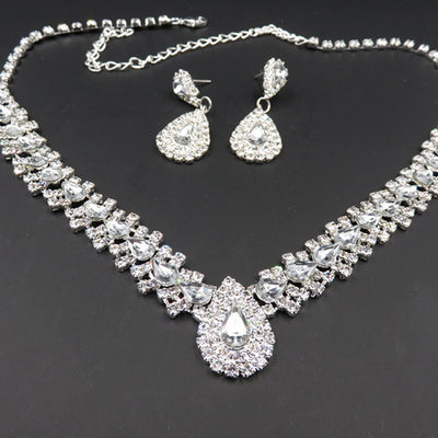 Sparkling silver-tone bridal jewelry set with a rhinestone necklace and matching teardrop drop earrings on a black bust. - Image 3