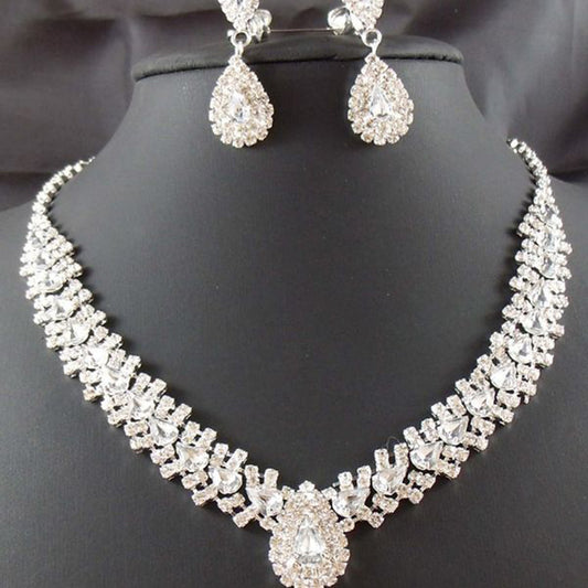 Sparkling silver-tone bridal jewelry set with a rhinestone necklace and matching teardrop drop earrings on a black bust.