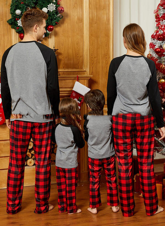 Family of four wearing matching gray and red plaid Christmas pajamas with reindeer graphic, standing by a festive fireplace and Christmas tree. - Image 2