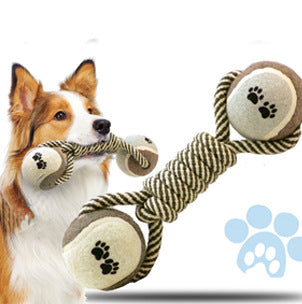 Braided rope dog chew toy with two tennis balls featuring paw prints, shown with a dog holding a similar toy.