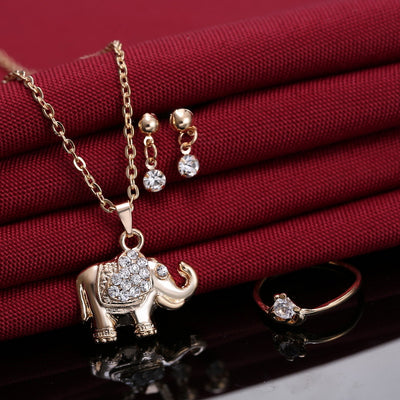 Rose gold-toned jewelry set with an elephant pendant necklace, matching rhinestone drop earrings, and a heart-knot ring. - Image 4